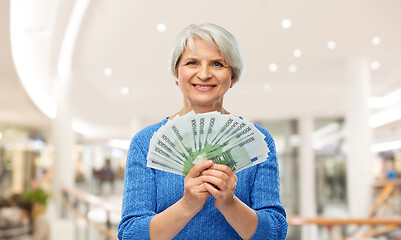 Image showing senior woman with euro money over shopping mall