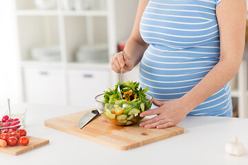 Image showing close up of pregnant woman cooking salad at home