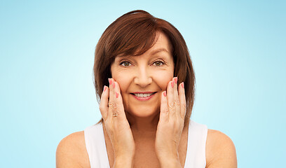 Image showing portrait of smiling senior woman touching her face