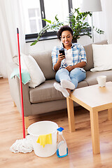 Image showing woman with smartphone resting after home cleaning