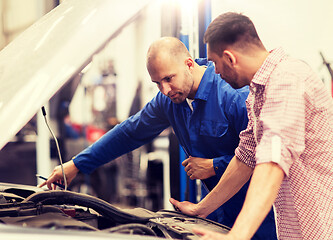 Image showing auto mechanic with clipboard and man at car shop