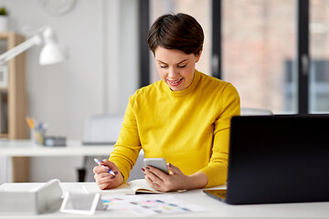 Image showing smiling ui designer using smartphone at office