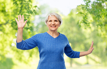 Image showing smiling senior woman touching something imaginary