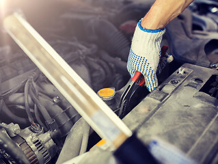 Image showing mechanic man with pliers repairing car at workshop