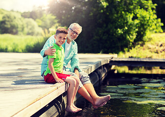 Image showing grandfather and grandson sitting on river berth