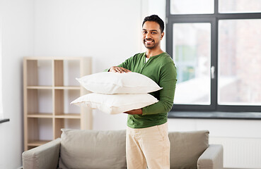 Image showing happy indian man holding pillows at home