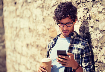 Image showing man with smartphone drinking coffee on city street