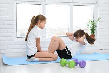 Image showing Older sister helps younger to do exercise for the press