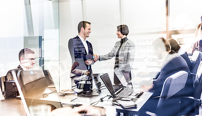 Image showing Confident business people shaking hands in moder corporate office.