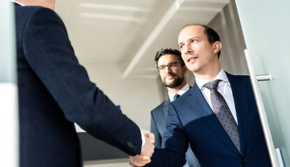 Image showing Group of confident business people greeting with a handshake at business meeting in modern office or closing the deal agreement by shaking hands.