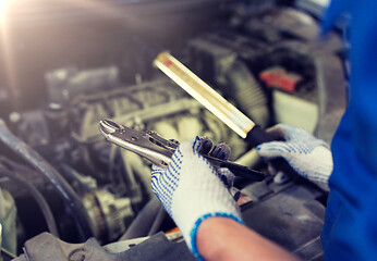 Image showing mechanic man with pliers repairing car at workshop