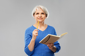 Image showing senior woman with pencil and diary or notebook