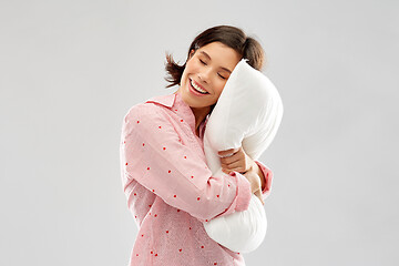 Image showing happy young woman in pajama hugging pillow