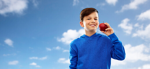 Image showing smiling boy in hoodie with red apple over blue sky