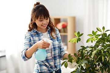 Image showing happy asian woman spraying houseplant at home