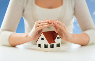 Image showing close up of woman protecting house model by hands