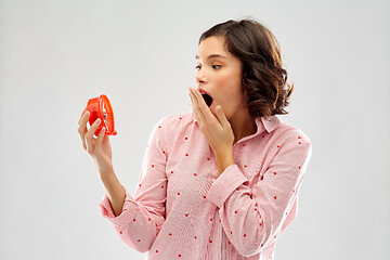 Image showing shocked young woman in pajama with alarm clock