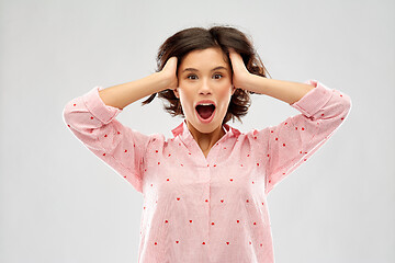 Image showing overwhelmed young woman in pajama holding to head