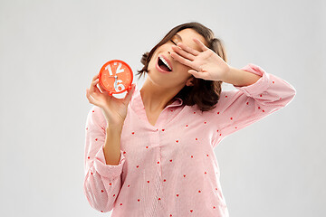 Image showing sleepy young woman in pajama with alarm clock