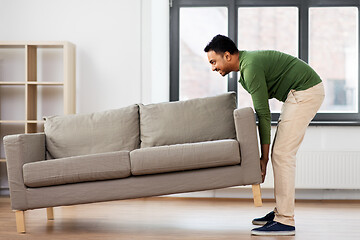 Image showing happy indian man moving sofa at home