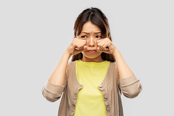 Image showing sad asian woman crying over grey background