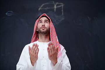 Image showing arabian man making traditional prayer to God, keeps hands in pra