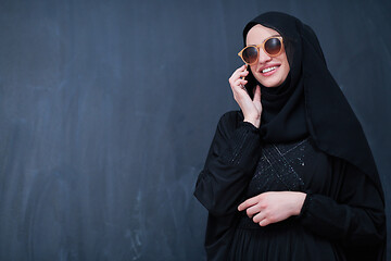 Image showing young muslim woman wearing sunglasses using smartphone