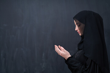 Image showing muslim woman making traditional prayer to God in front of black 