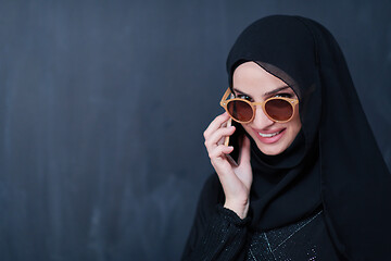 Image showing young muslim woman wearing sunglasses using smartphone