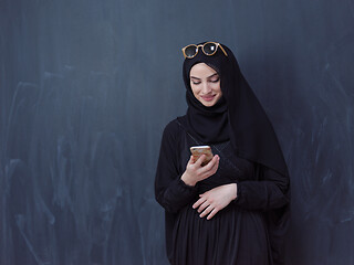 Image showing young muslim woman wearing sunglasses using smartphone