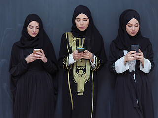 Image showing muslim women using mobile phone in front of black chalkboard