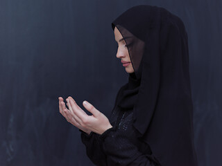 Image showing muslim woman making traditional prayer to God in front of black 