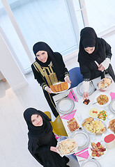 Image showing young muslim girls serving food on the table for iftar dinner to