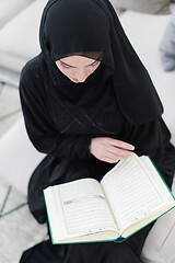 Image showing young muslim woman reading Quran at home