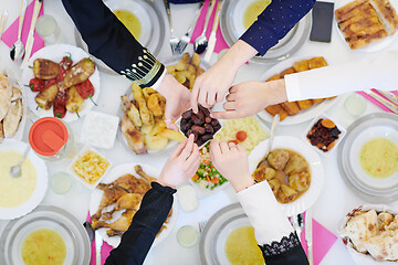 Image showing Muslim family having Iftar dinner eating dates to break feast to