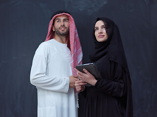 Image showing muslim couple using modern technology in front of black chalkboa