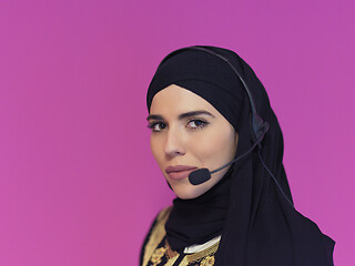 Image showing portrait of muslim woman with headset on pink background