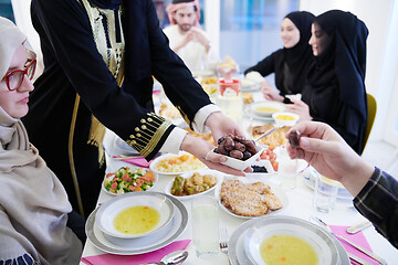 Image showing Muslim family having Iftar dinner eating dates to break feast