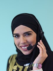 Image showing muslim woman with headset on cyan background