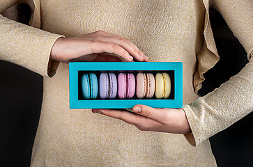 Image showing Female hands hold macaroons in box