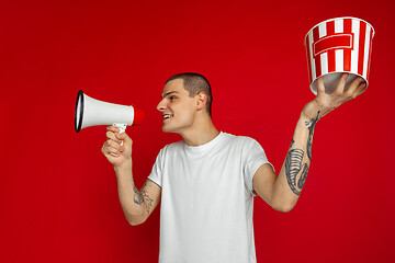 Image showing Caucasian young man\'s portrait on red studio background, emotinal and expressive, cinema concept