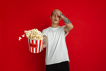 Image showing Caucasian young man\'s portrait on red studio background, emotinal and expressive, cinema concept