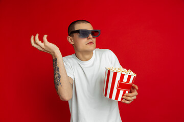 Image showing Caucasian young man\'s portrait on red studio background, emotinal and expressive, cinema concept