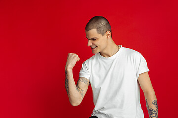 Image showing Caucasian young man\'s portrait on red studio background, emotinal and expressive