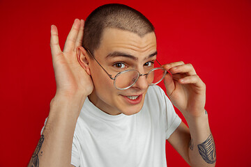 Image showing Caucasian young man\'s portrait on red studio background, emotinal and expressive