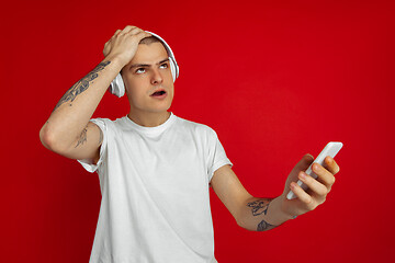 Image showing Caucasian young man\'s portrait on red studio background with copyspace - emotional and expressive, angry and upset