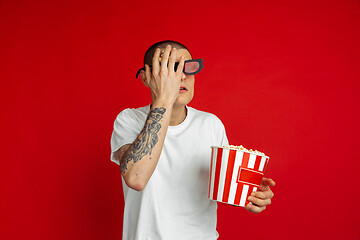 Image showing Caucasian young man\'s portrait on red studio background, emotinal and expressive, cinema concept