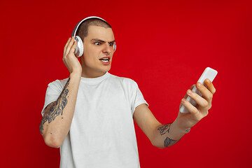 Image showing Caucasian young man\'s portrait on red studio background with copyspace - emotional and expressive, angry and upset