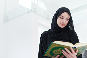 Image showing young muslim woman reading Quran at home