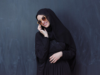 Image showing young muslim woman wearing sunglasses using smartphone